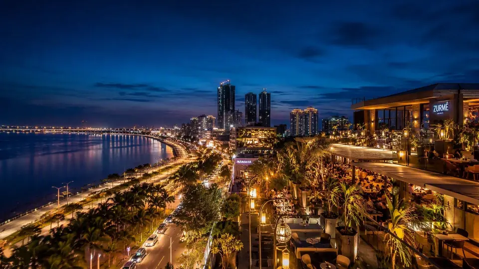 Illuminated Surat skyline along the Tapi riverfront at dusk with upscale restaurants and lounges